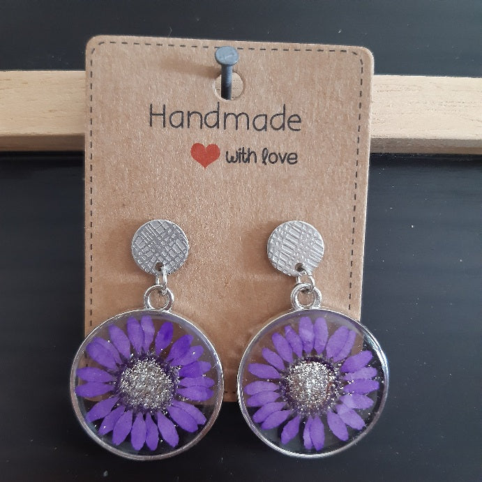 Boucles d'oreilles en résine artisanale composées d'une vraie fleur de marguerite violette naturelle séchée
