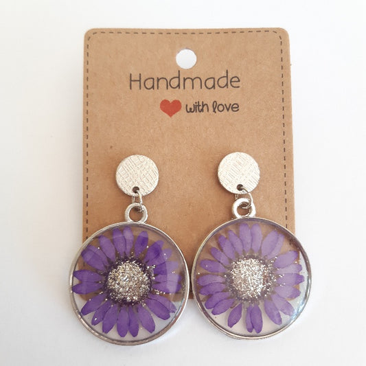 Boucles d'oreilles en résine artisanale composées d'une vraie fleur de marguerite violette naturelle séchée